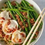 A colorful plate of beans paired with fried rice and dumplings, showcasing vibrant ingredients