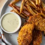 Crispy baked chicken tenders served with fries and mustard dipping sauce on a plate.