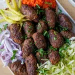 Juicy beef cevapi paired with sliced onions and pita