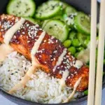 Bowl of honey soy glazed salmon fillet topped with sesame seeds and green onions, served with a side of steamed rice and vegetables