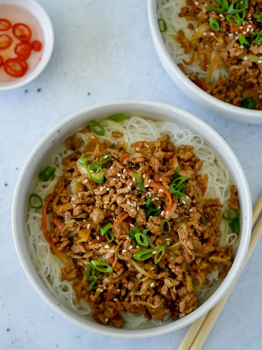 Two spring roll bowls with a side of vinegar and chilli with chopsticks.