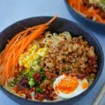 Bowl of ramen noodles with ground meat, corn, carrots, and soft-boiled egg