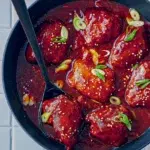 Slow cooker honey garlic chicken served in a pan, topped with fresh spring onions