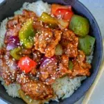Sweet and sour pork dish featuring vibrant bell peppers and a glossy sauce, served in a bowl