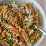 Creamy Parmesan chicken pasta plated with a spoon and herb garnish