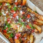 Beef Brisket Loaded Fries, topped with melted cheese, tender beef brisket, and fresh garnishes.