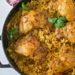 Overhead view of Chicken Korma Bake in a pan, featuring tender chicken pieces in a creamy sauce garnished with fresh herbs.