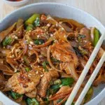 A bowl of Drunken Noodles with chopsticks resting on top