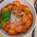 Creamy sausage gnocchi in a bowl, topped with herbs