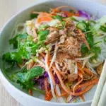 Bang Bang Chicken Salad served in a bowl with chopsticks resting on the rim.