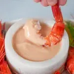 Close-up of a prawn dipped in Cocktail Sauce, showcasing its creamy texture and fresh ingredients