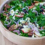Side view of a bowl of maple kale salad with dried cranberries and blue cheese.