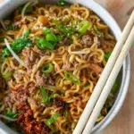 Close-up shot of beef ramen noodles and a pair of chopsticks on top.