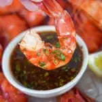 Prawn being dipped into Sweet Chilli Lime Sauce, highlighting the creamy and flavorful texture.