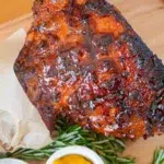 Close-up of a whole glazed ham on a wooden board, highlighting the caramelized glaze and rich texture.