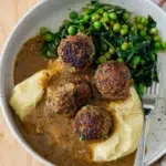 Meatballs in rich, smooth gravy on a plate.