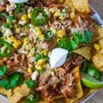 Slow cooker chicken nachos topped with melted cheese, served on a plate.