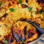 Freshly baked moussaka being served, highlighting its golden topping.
