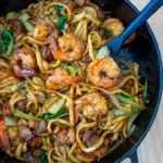 Malaysian-inspired Hokkien Mee served in a black pan with a spatula.
