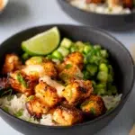 Crispy Bang Bang salmon pieces drizzled with creamy sauce, served in a black bowl.