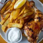 Overhead view of Portuguese chicken and chips on a plate.