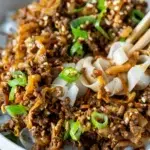 Close-up of Sticky Hoisin Beef with chopsticks in beef and noodles