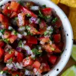 Close-up of classic pico de gallo in a bowl, made with ripe tomatoes, red onion, chili, coriander, lime, and salt