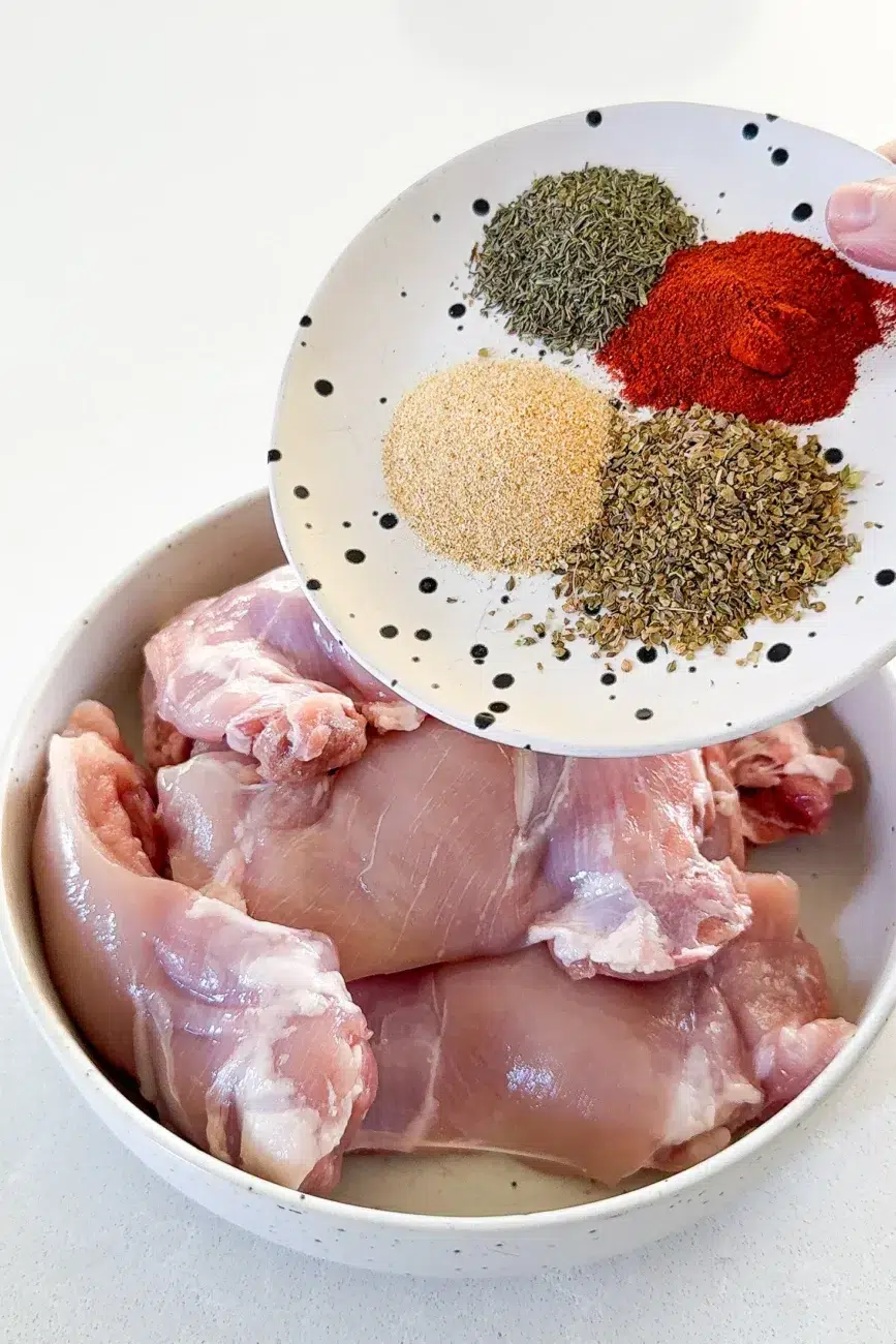 Spices and herbs being added to chicken