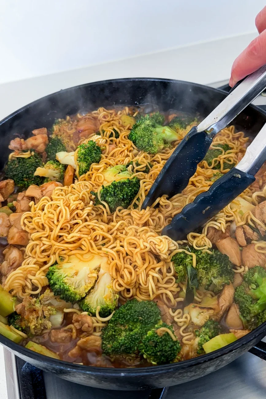 Ramen noodles noodles being tousled with tongs during cooking