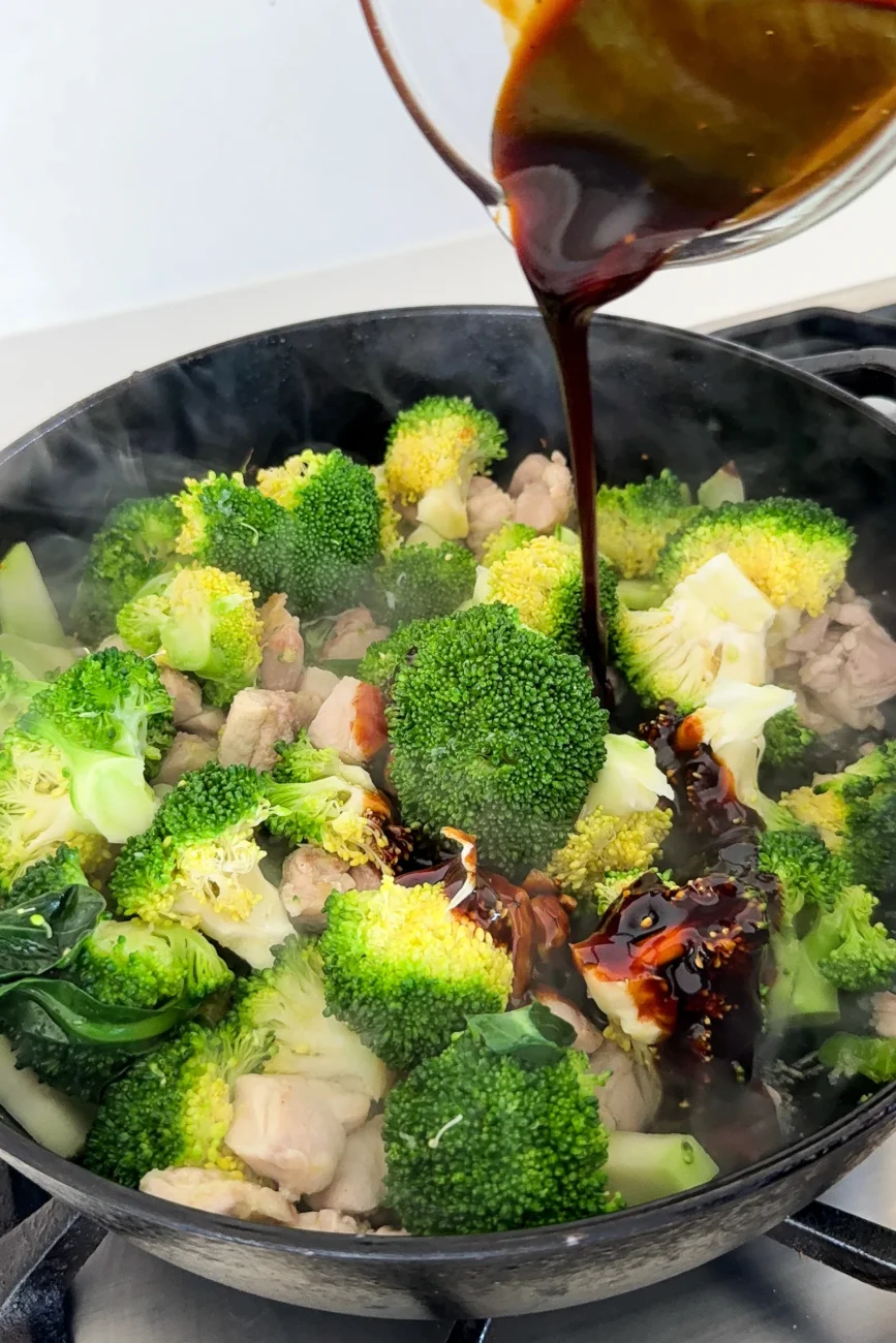 Sauce being added to steamed broccoli and chicken