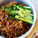 One-pan Korean-style beef noodles topped with sesame seeds, cucumber and spring onion