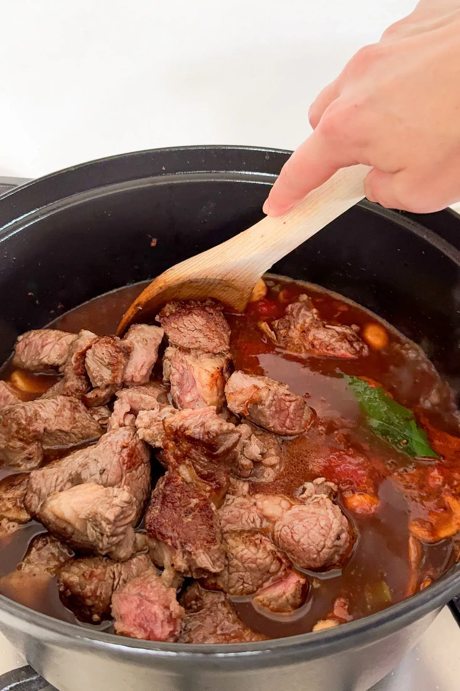 Beef ragu ingredients simmering together in a deep pan