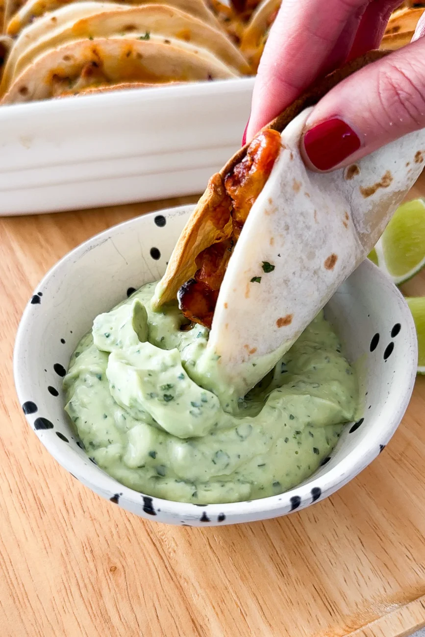 Taco being dipped in avocado cream