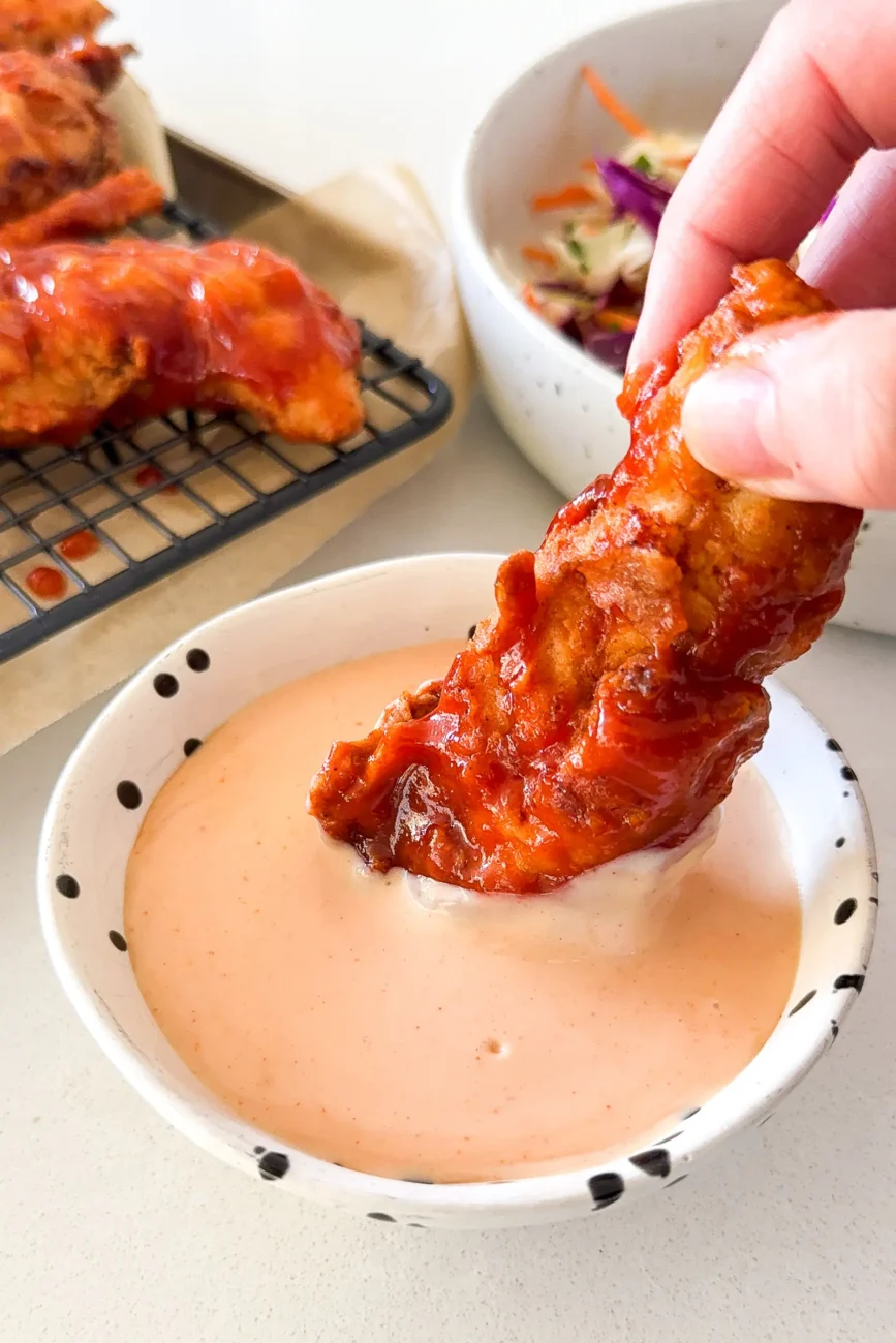 Chicken tender being dipped into comeback sauce