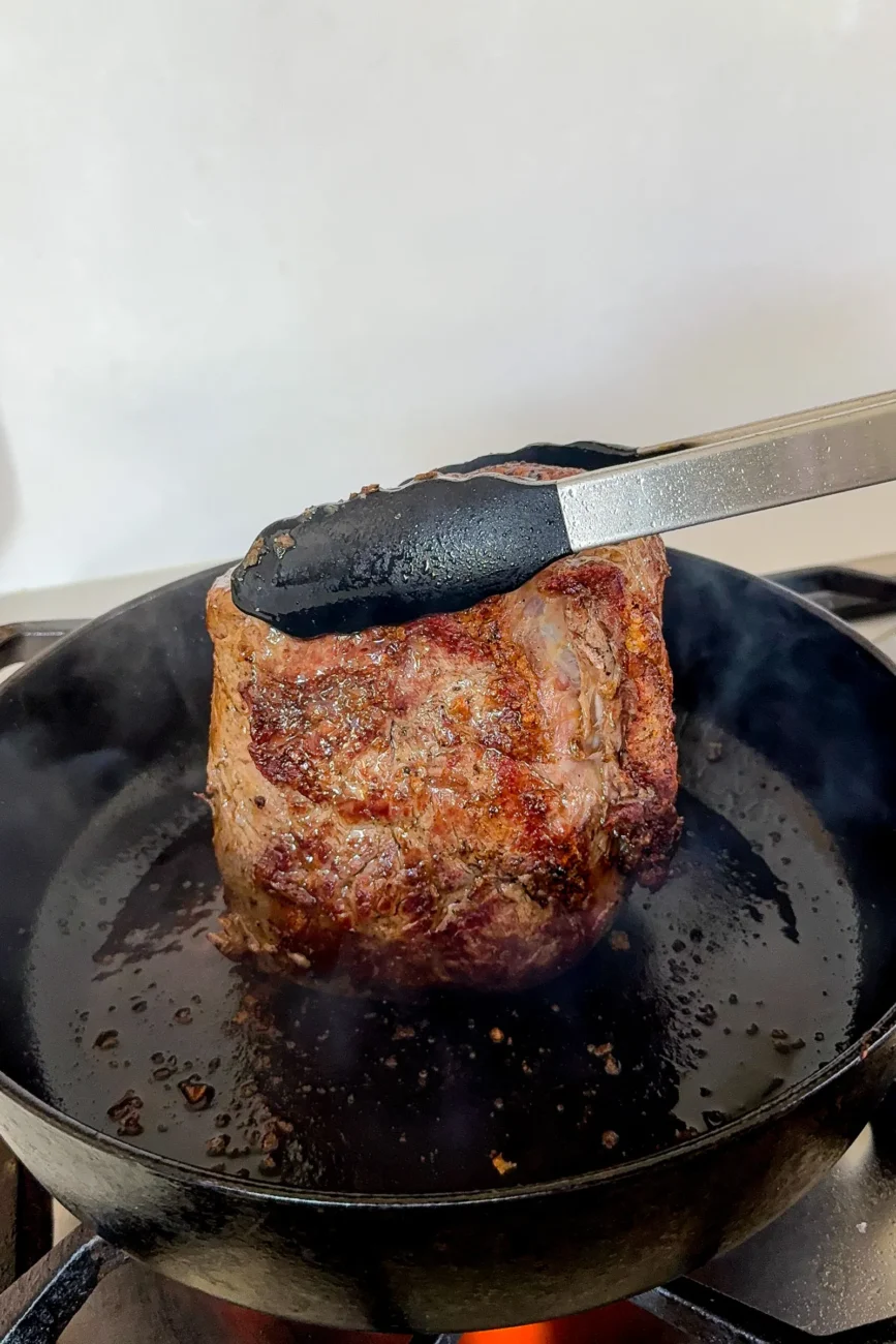 Chuck roast being seared and turned on side so that it is seared on all sides