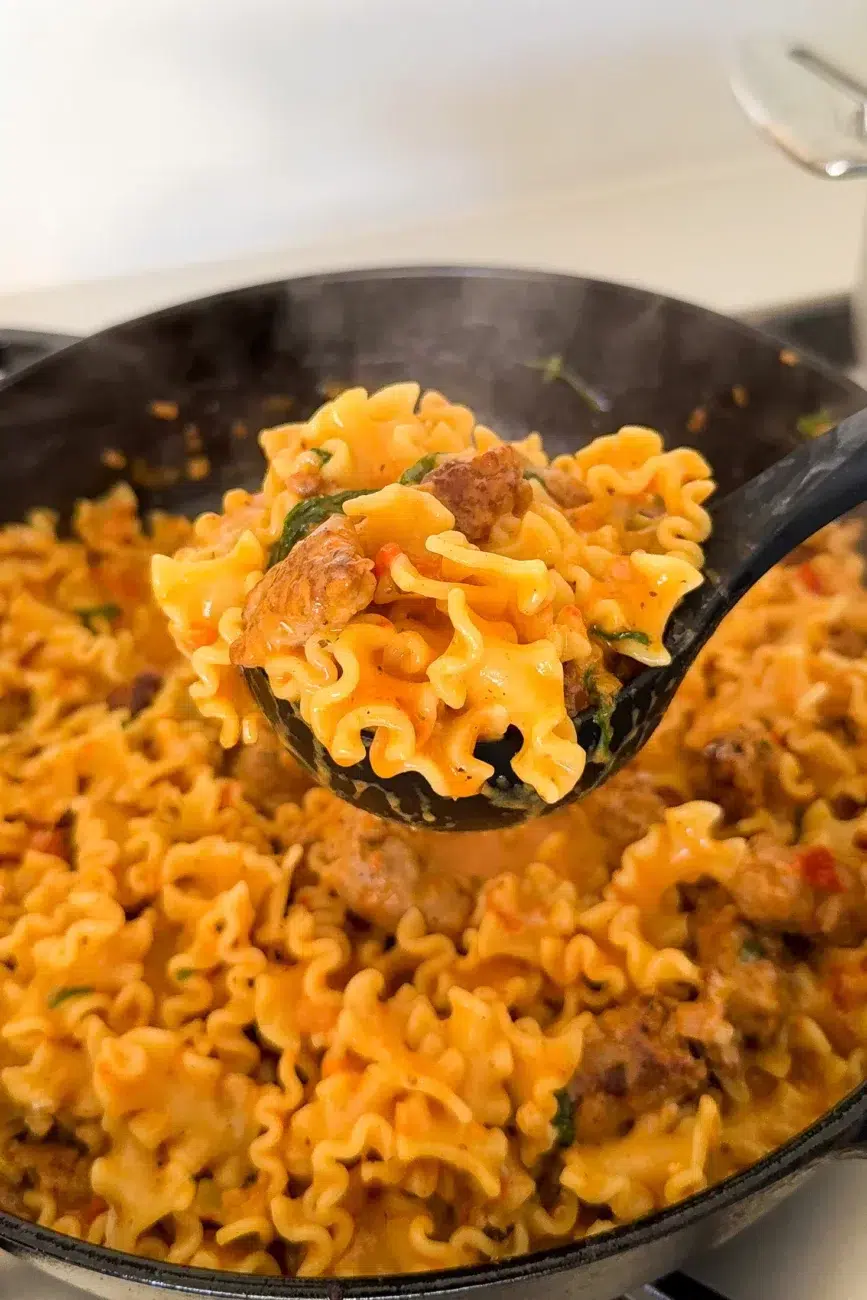 Finished pasta being ladled out of pan
