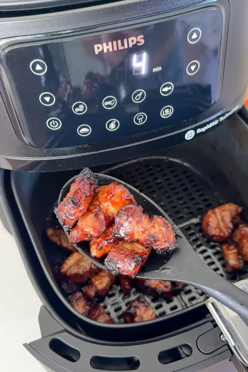 Finished pork belly being scooped out of air fryer