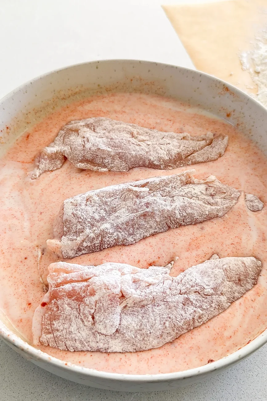 Flour dusted chicken tender added to wet ingredients