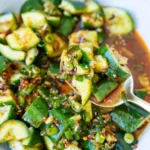 Smashed asian cucumber salad being scooped with spoon