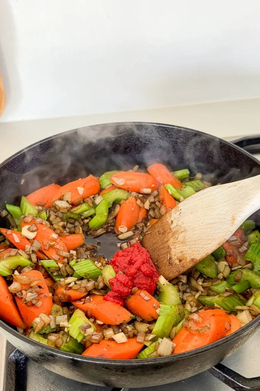 Tomato paste is added to the vegetables for richness and depth