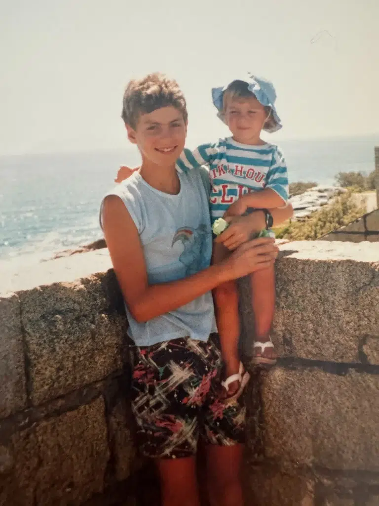 Young Nicole being held by her older brother Roman by the sea