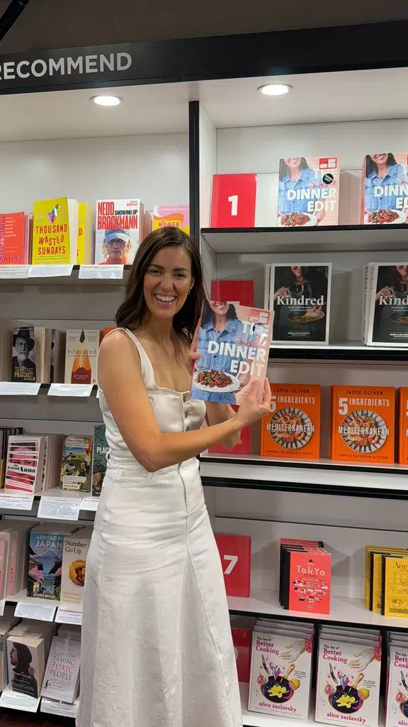 Nicole Maguire holding her first cookbook, The Simple Dinner Edit, in a bookshop