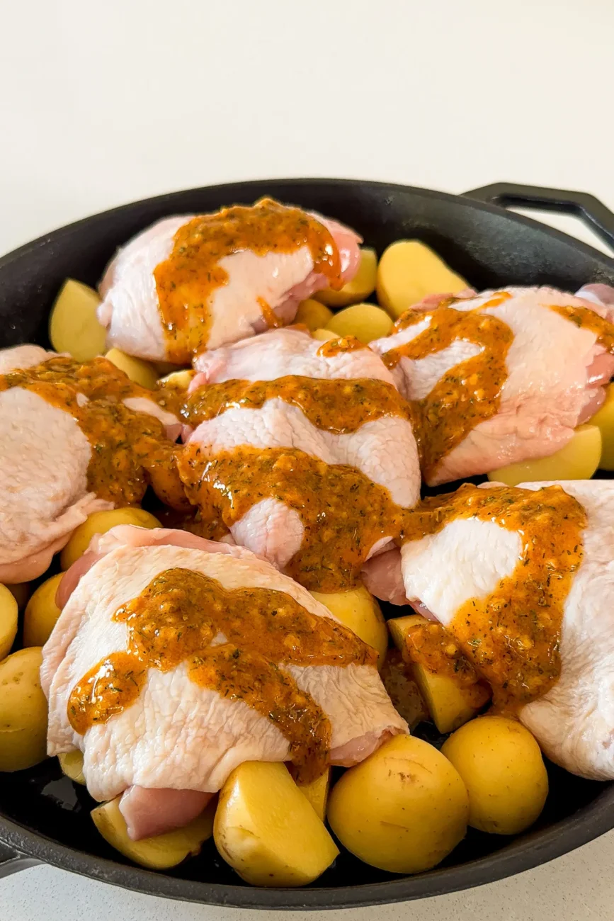 Chicken nestled on potatoes with marinade poured in