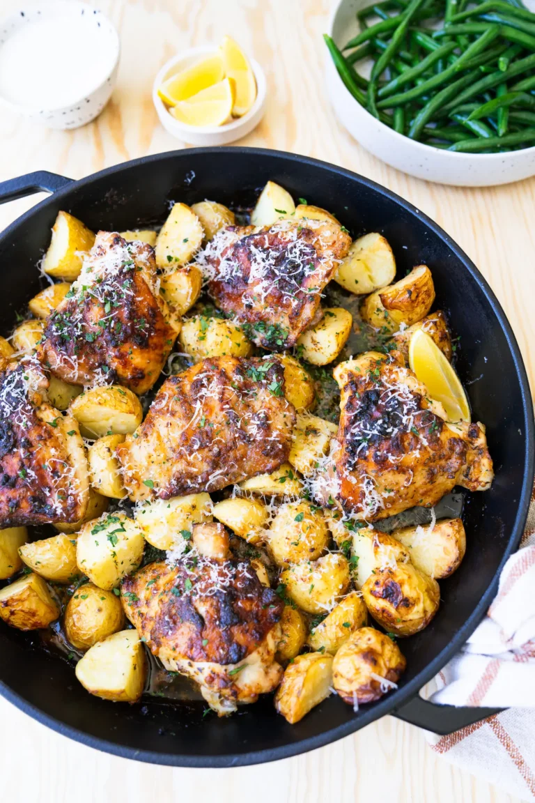 Top view chicken in baking dish with side of greens and lemon