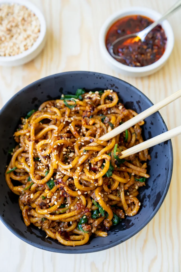 close up dan dan noodles in bowl with chopsticks