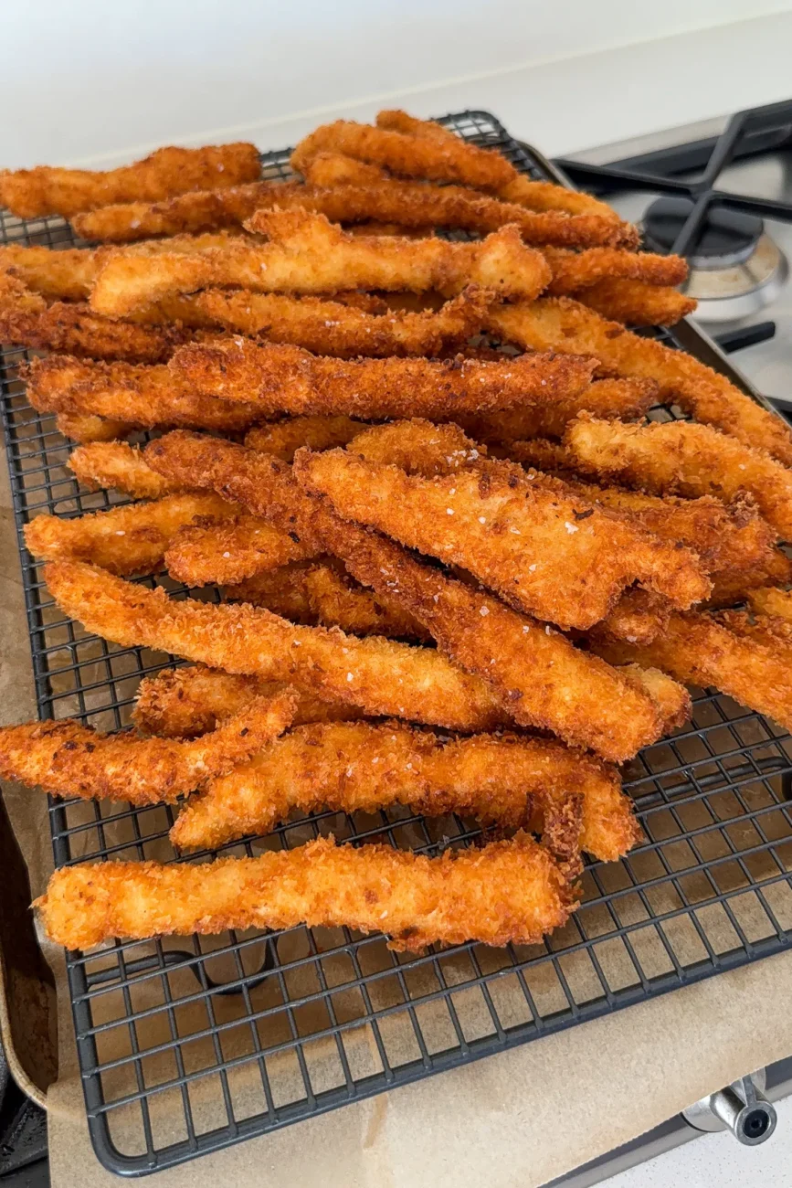 cooked chicken fingers cooling on wire rack