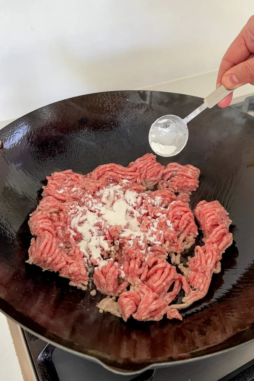 cornflour being sprinkled on pork