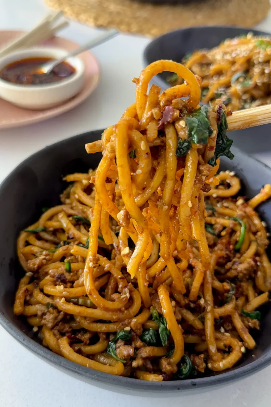 noodles being lifted out of bowl with chopsticks showing stretch