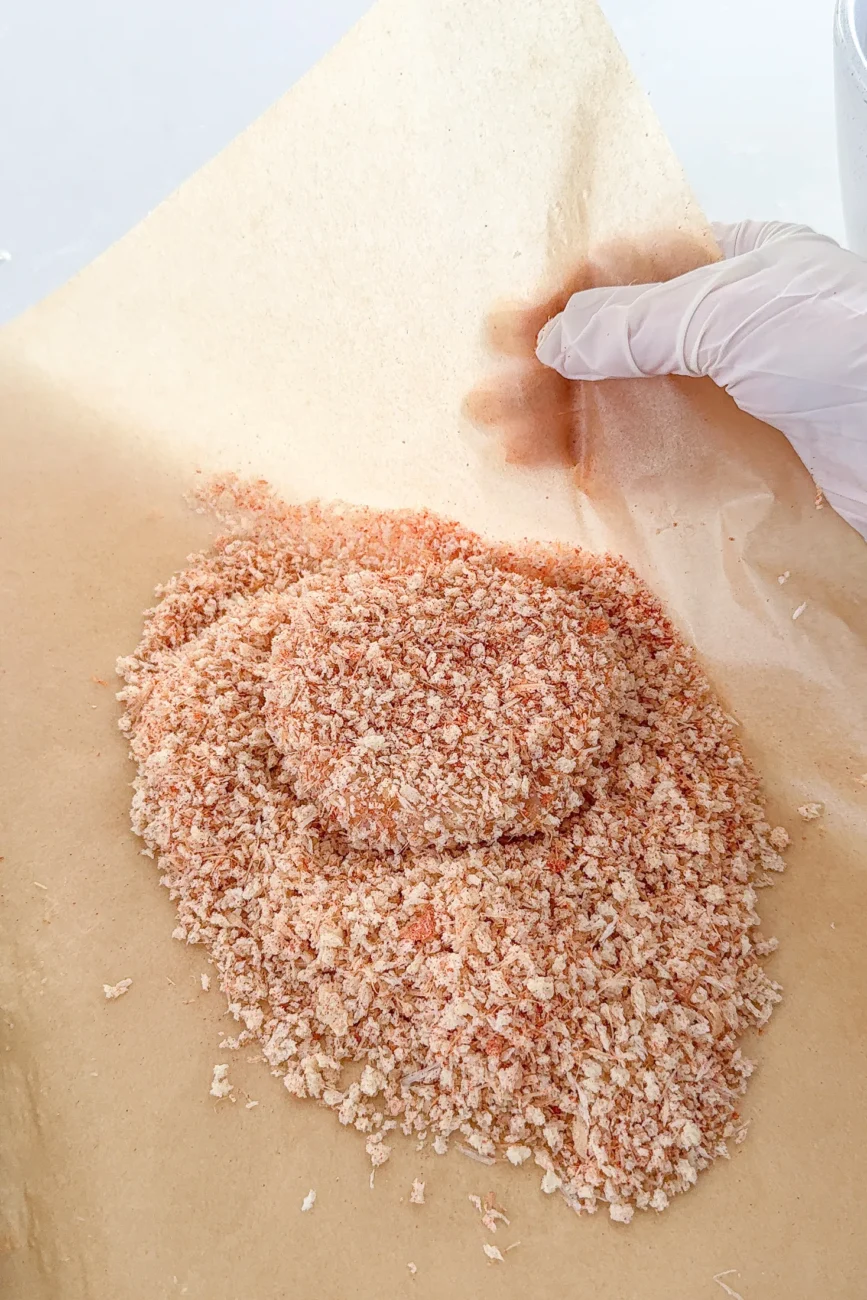 Chicken burger patties being coated in parmesan panko crumbs
