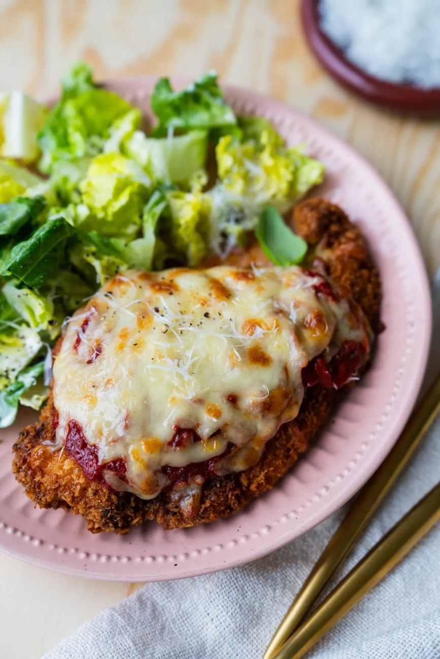 Chicken parmigiana plated with Caesar dressing